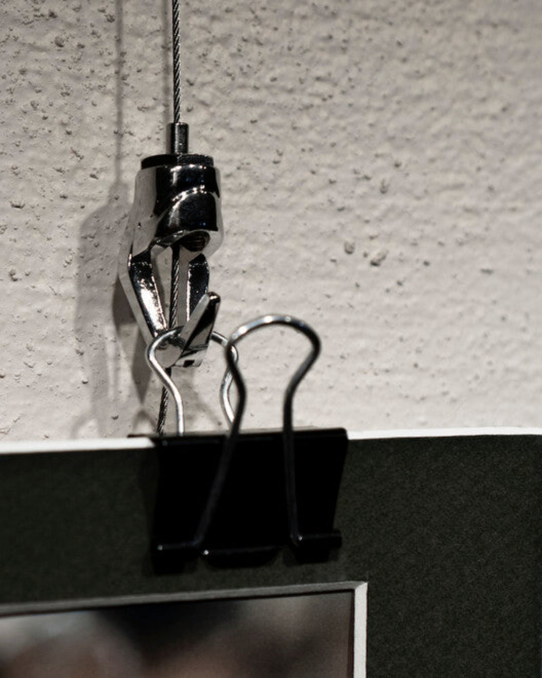 binder clip used to attach unframed piece of art to hook on art hanging system