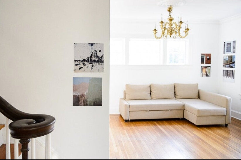 Interior of home showing two small groupings of photographs, one on stairway wall, one in corner of living room