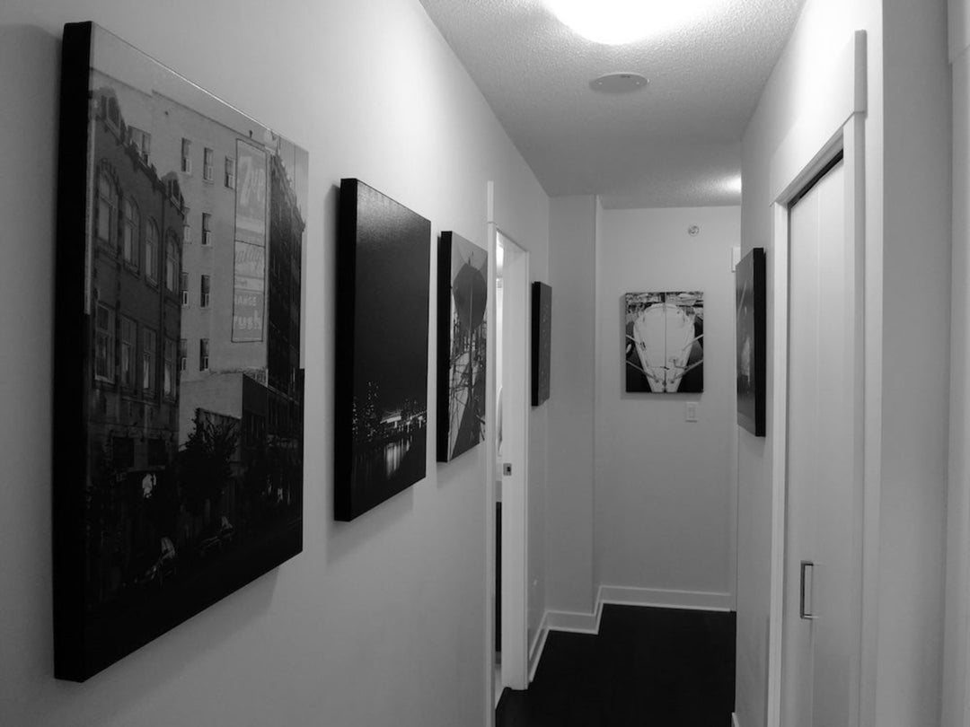 paintings hung in a home corridor with harsh, shadowy lighting