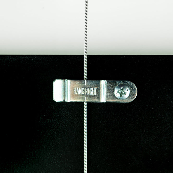 In-use image of HangRight clip, used on picture rail molding and art hanging systems to keep artworks hanging straight