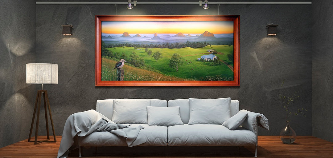 Living room with sofa, featuring large landscape painting hung on a wall mounted picture hanging system with integrated art lighting