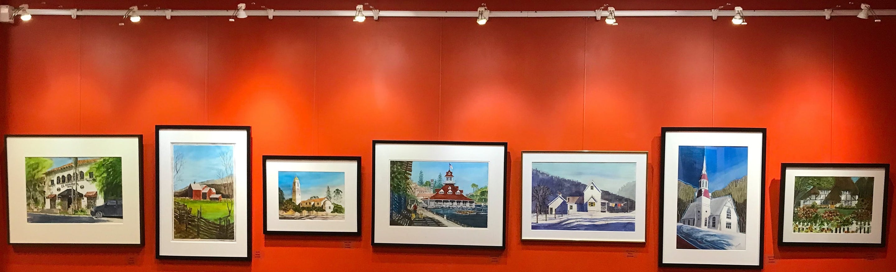 row of seven paintings hung on art gallery hanging system with integrated lighting