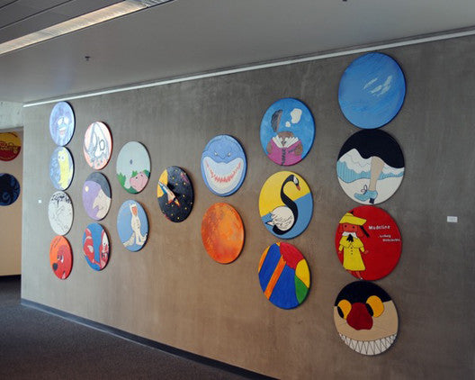 art hanging system being used to display circular paintings with images from children's books in library 