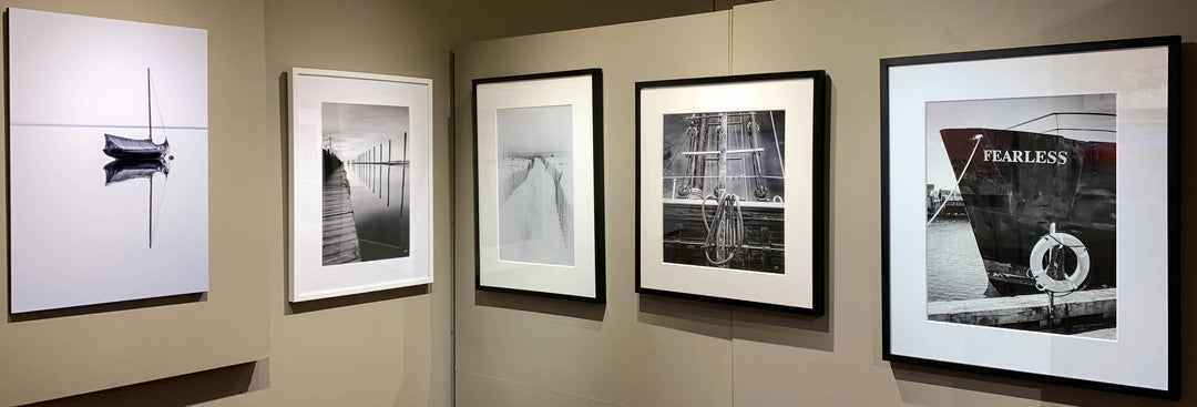 Five black-and-white photos of nautical and waterfront scenes, taken by Bobby Baker and displayed at the Cape Cod Maritime Museum