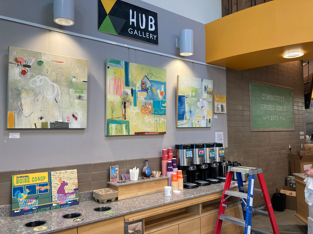 art gallery area near coffee counter at food co-op, displaying abstract paintings using art gallery hanging system