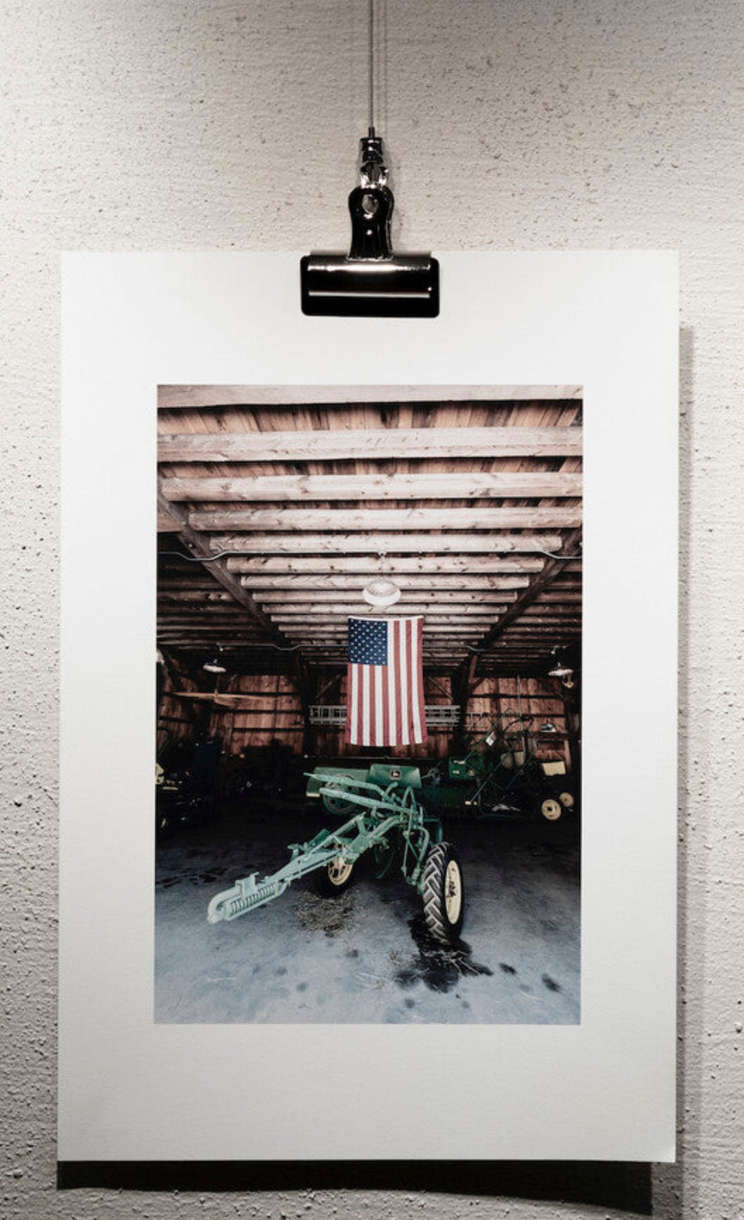 bulldog clamp being used to connect an unframed photo to hook on picture hanging system