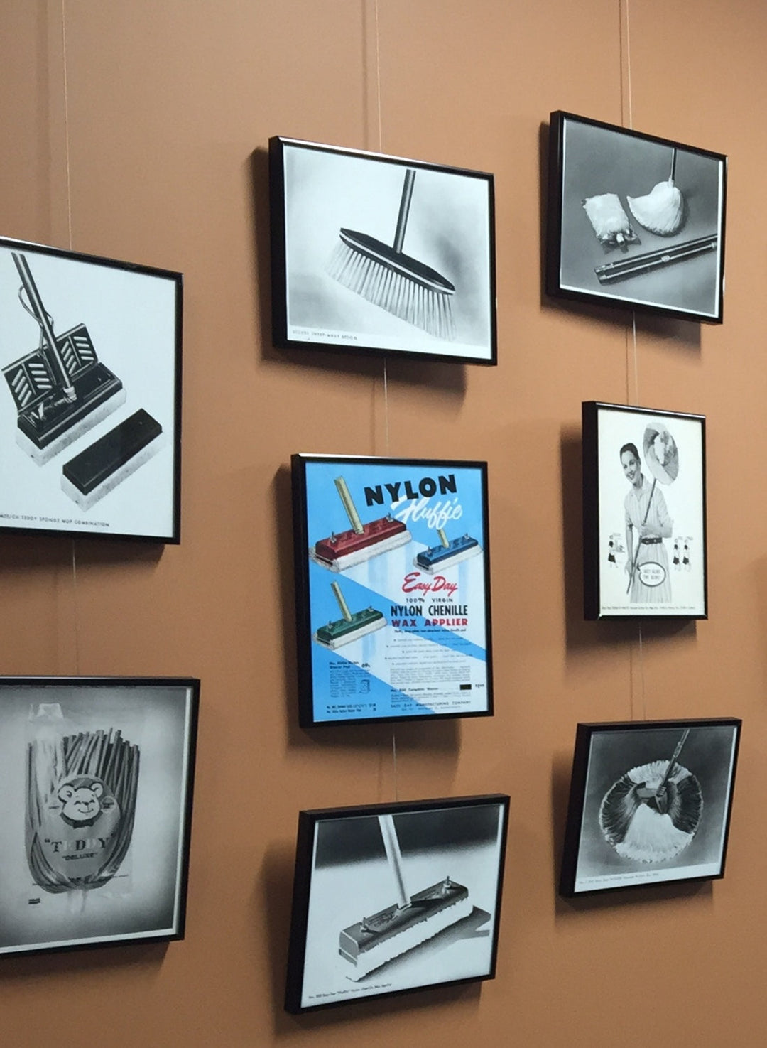vintage advertisements and photos displayed on a picture hanging system
