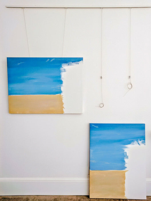 Home art studio with installed picture hanging system being used to display unfinished work-in-progress landscape paintings on steel cable hangers