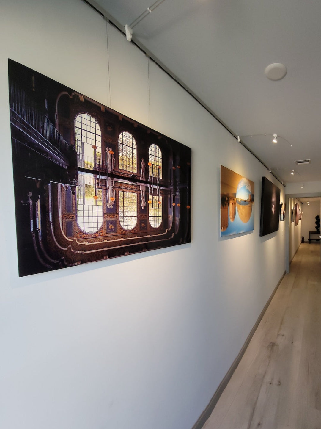 Corridor at law firm office used to display artworks on wall-mounted art gallery hanging system 