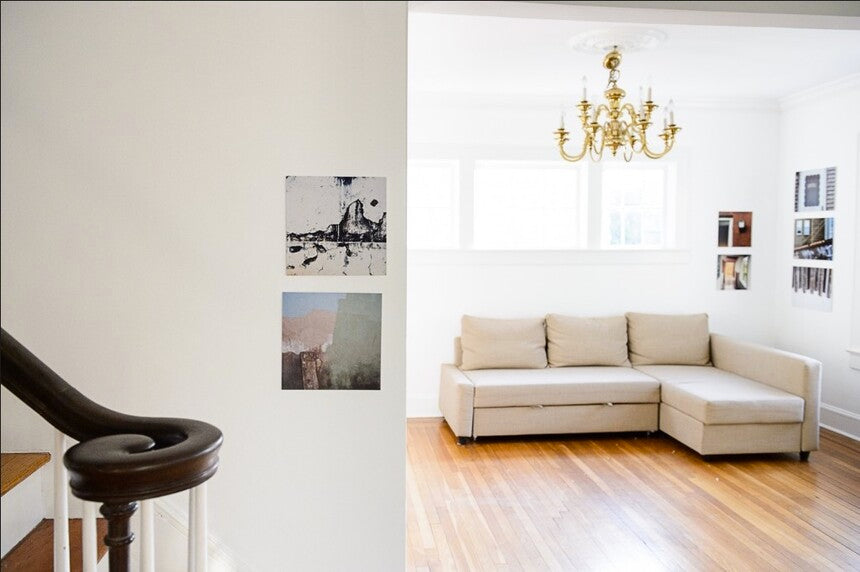 Interior of home showing two small groupings of photographs, one on stairway wall, one in corner of living room