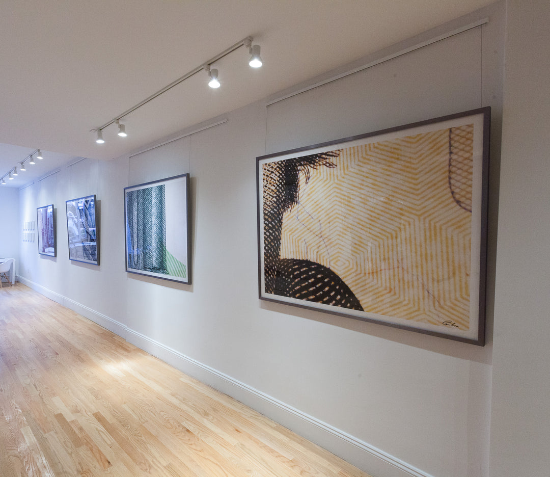 Interior of upscale art gallery showing very large abstract paintings hung on wall mounted picture hanging system