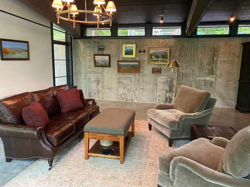 living room with concrete wall where art is being displayed on a picture hanging system