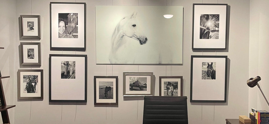 artist's gallery wall display of drawings photos on wall-mounted art hanging system 