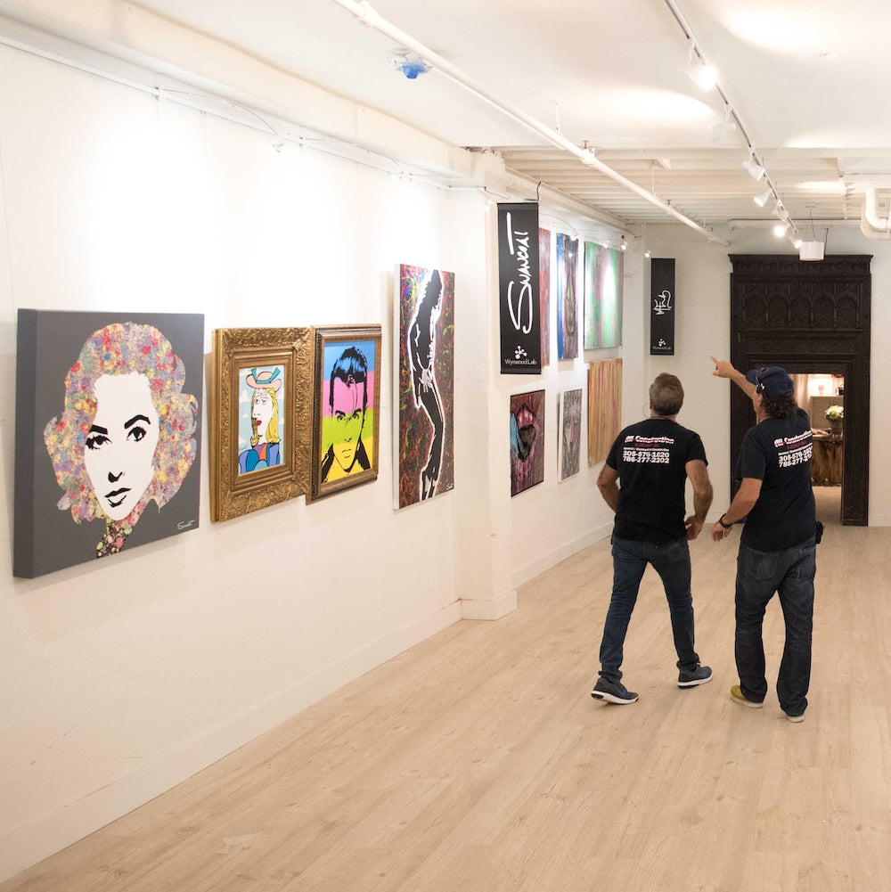 workers at an art gallery pointing to a wall equipped with a picture hanging system that is being used to display modernist artworks 