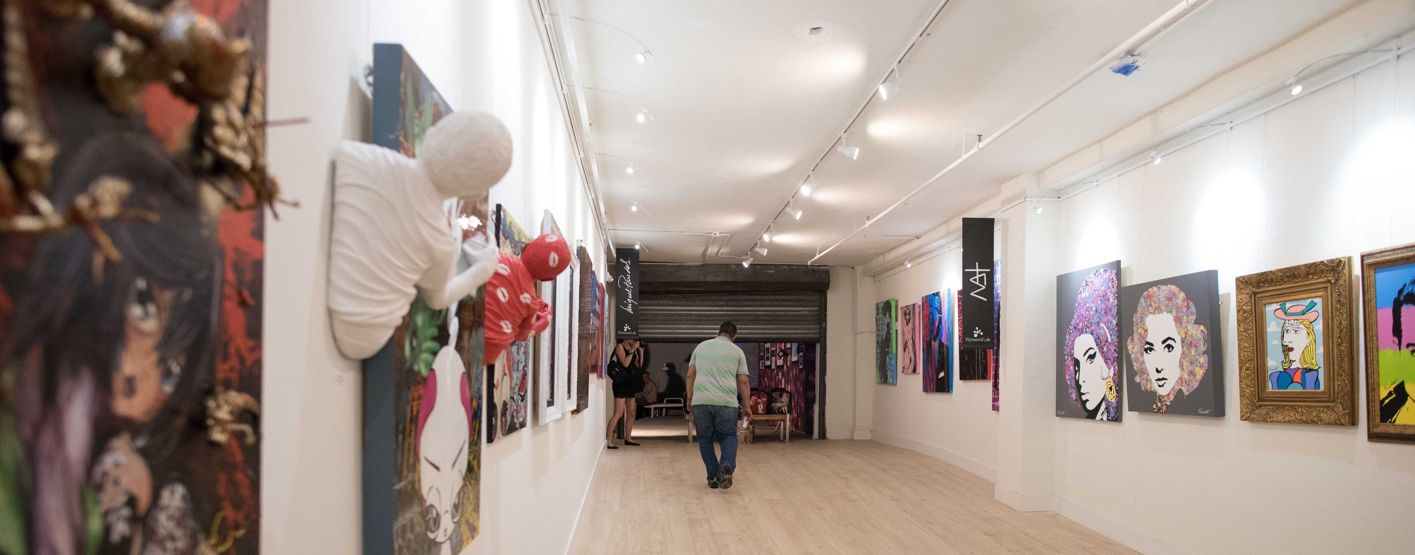 art works hung on picture hanging system at art gallery, with integrated art lighting as well as ceiling track lights