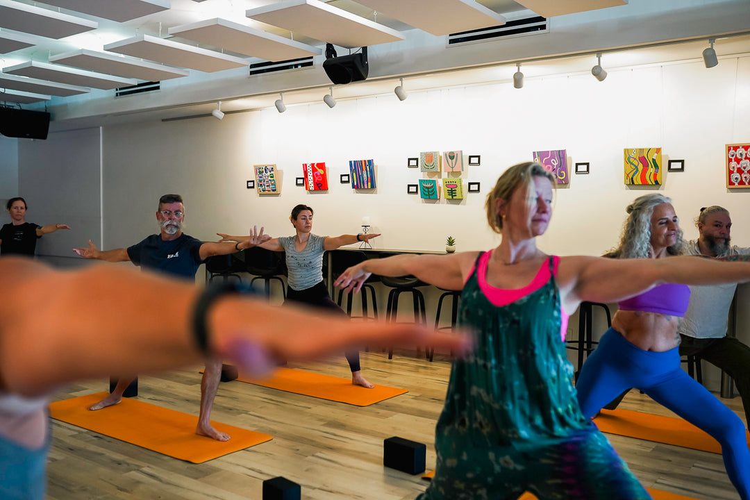 Yoga class being conducted in a room with an art gallery display on the wall
