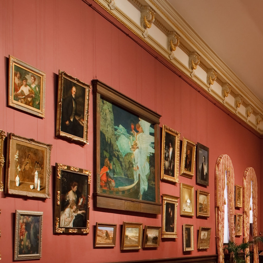 large salon-style exhibition of about 17 paintings of different sizes hung using picture rail molding art hangers