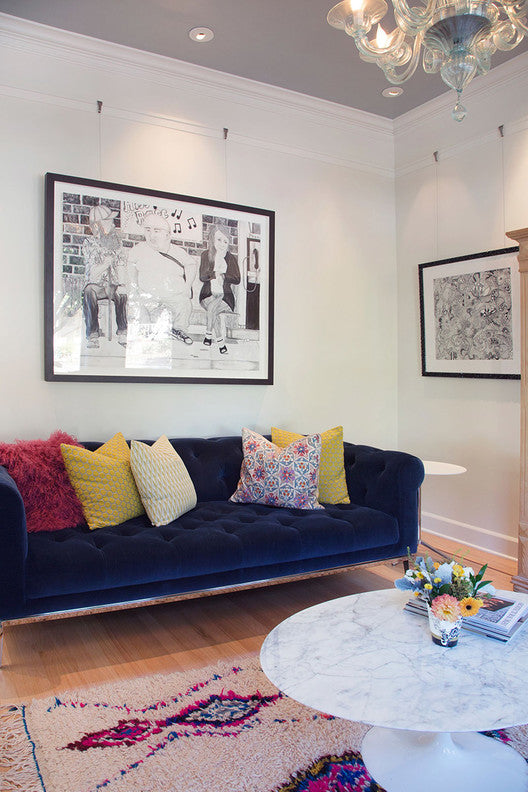 living room with artworks hung on picture rail molding with art hanging system hangers, illuminated by ceiling light fixtures
