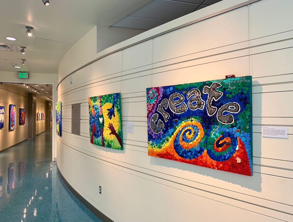 curved wall in hospital lobby, equipped with an art rail hanging system that is being used to display several brightly colored paintings