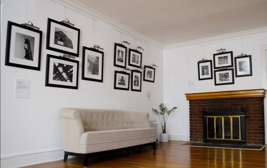 three groups of photos hung on picture hanging systems; each photo is provided with an individual picture light for art lighting