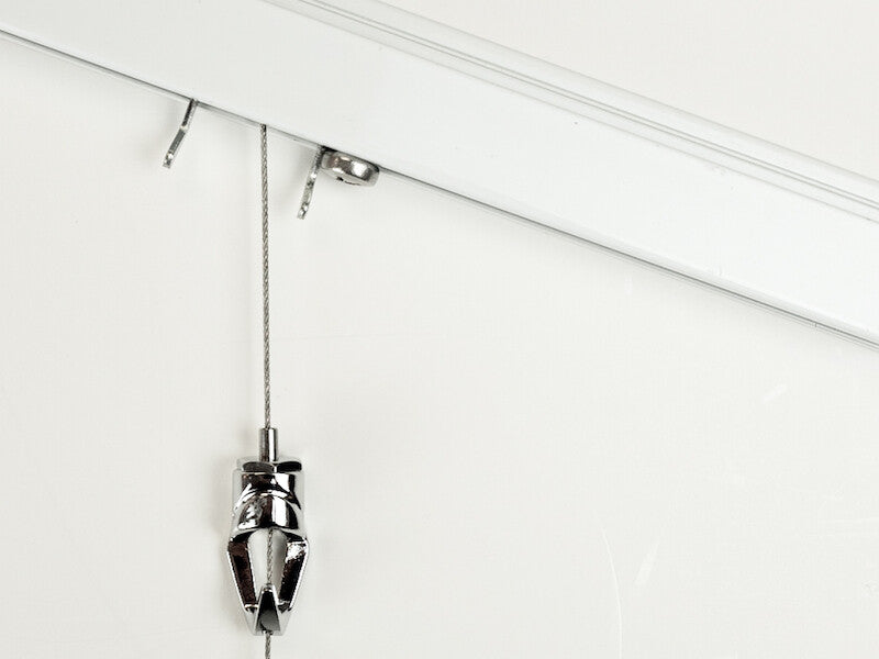 wall track of a picture hanging system mounted at an angle with steel cable hanger and pushbutton art hanging hook inserted