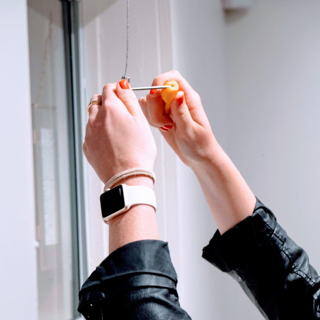 closeup of art gallery curator using a wrench to adjust the position of a hook on a picture rail art hanging system