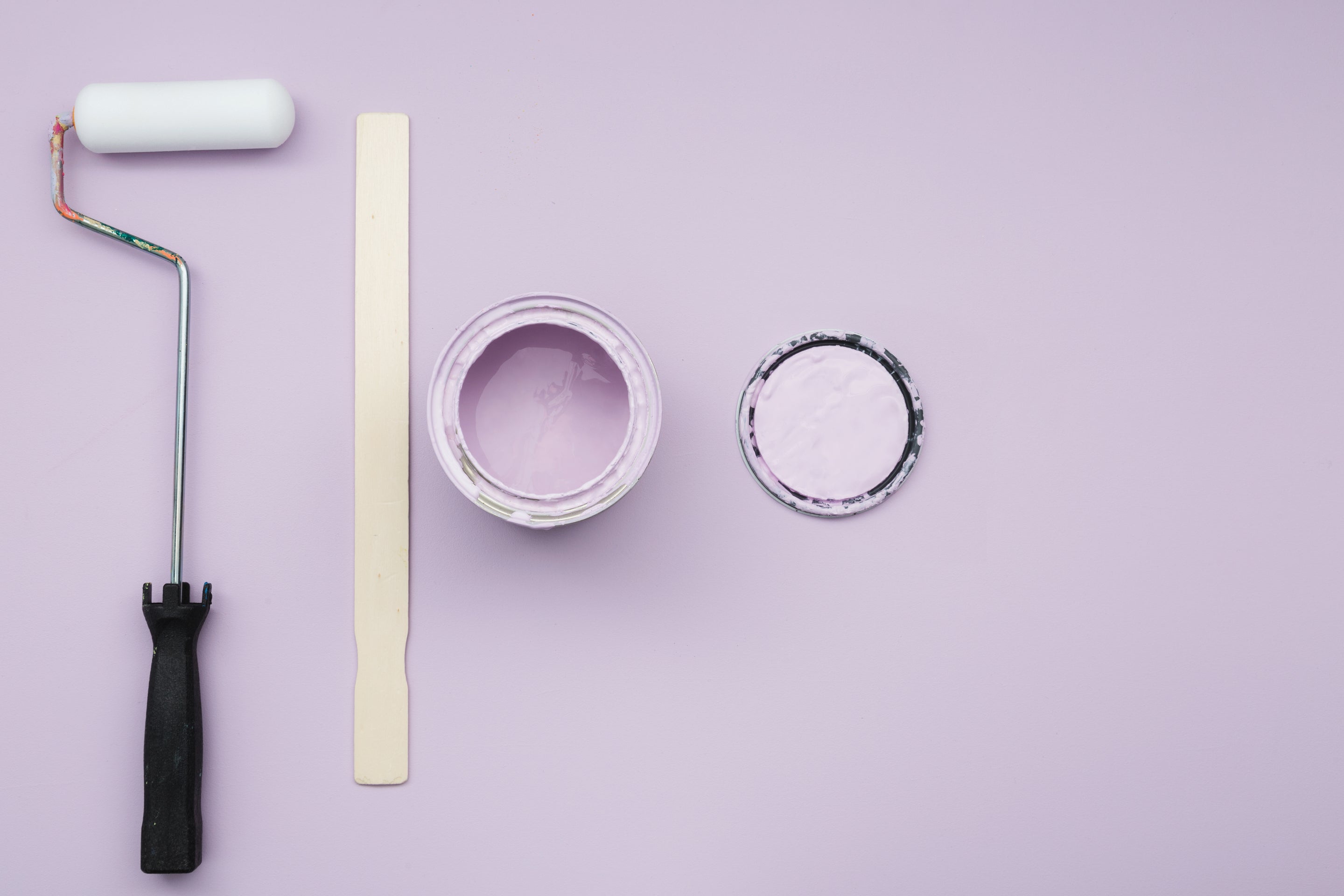 open can of purple paint along with stirring stick, lid, and paint roller 