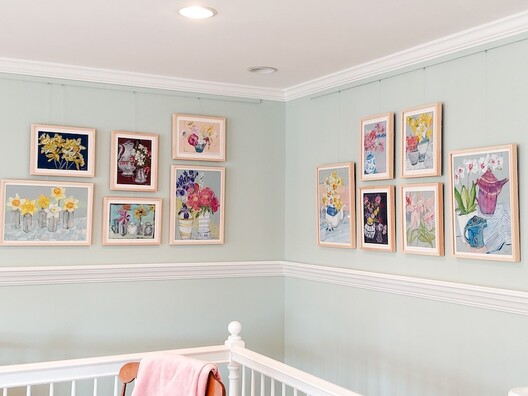 Display of art in corner of room over staircase using picture hanging system