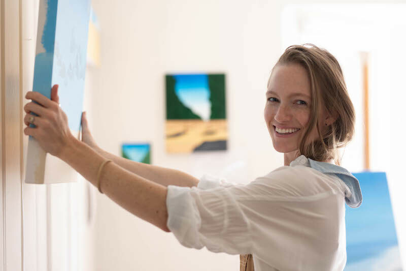 Artist hanging painting on picture hanging system in home studio
