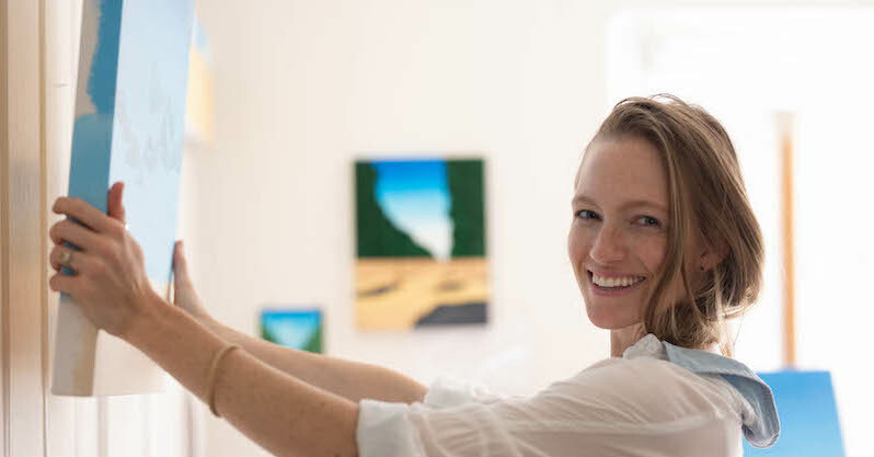Artist Haley Coleman hangs a painting in her home studio using a picture hanging system